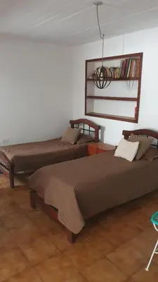 a bedroom with two beds and a shelf with books at Casa en Nono a 200 metros del lago in Las Rabonas