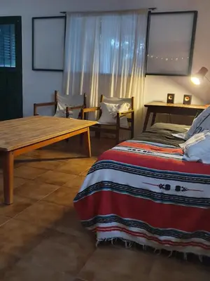 a bedroom with a bed and a wooden table at Casa en Nono a 200 metros del lago in Las Rabonas