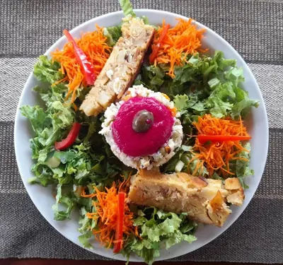 a white plate with a salad with carrots and other foods at Hostería Vegetariana in Country Club Chumamaya