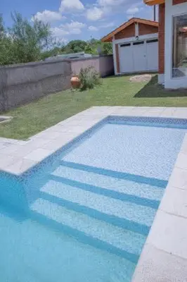 a blue swimming pool in a yard with a house at Casa entera in Mina Clavero