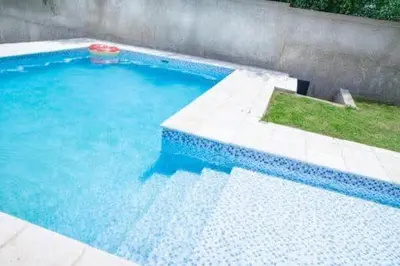 a large swimming pool with blue water and grass at Casa entera in Mina Clavero