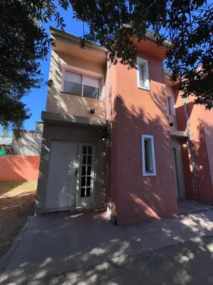 a red building with a door and a garage at Dúplex Juncal in Villa Carlos Paz