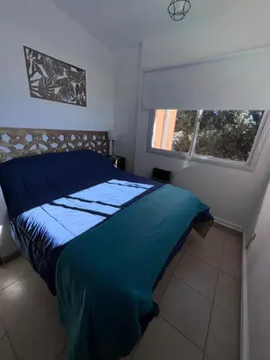 a bedroom with a blue bed and two windows at Dúplex Juncal in Villa Carlos Paz