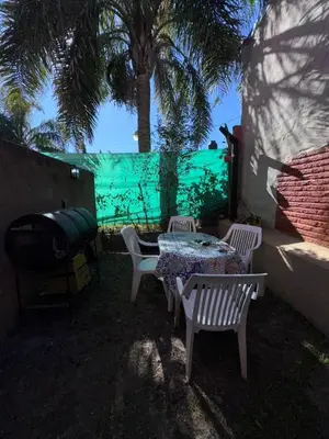 a patio with a table and chairs and a palm tree at Dúplex Juncal in Villa Carlos Paz