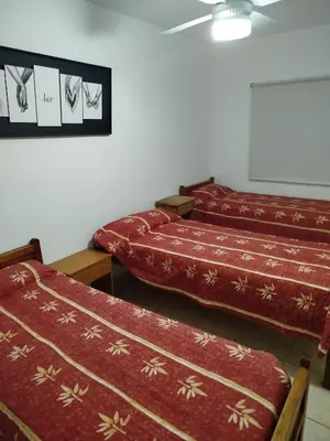 a room with two beds and a white wall at El Paraiso in Villa Carlos Paz