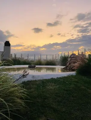 a pond in the grass with a city in the background at Depto con hermosas vistas, centro con solarium y seguridad in Cordoba