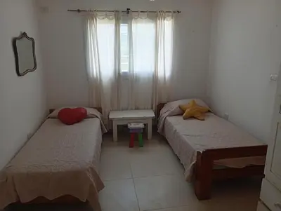two beds in a small room with a window at Hermosa casa a 15 min de Villa Carlos Paz in Villa Santa Cruz del Lago