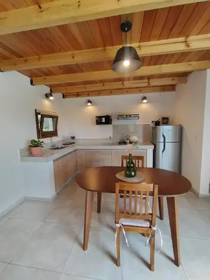 a kitchen with a wooden ceiling and a wooden table and chairs at Las Calandrias II in Los Reartes