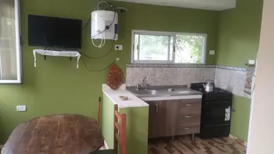 a kitchen with green walls and a sink and a table at Las Lomitas 2 in Villa Cura Brochero
