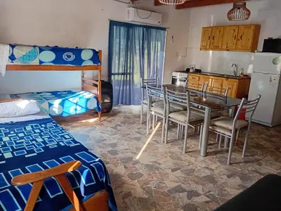 a room with a table and chairs and a kitchen at La Gringa in Villa Parque Siquiman