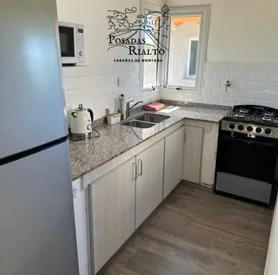 a kitchen with a sink and a stove and a refrigerator at cabañas RIALTO in Villa Amancay