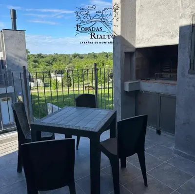 a table and chairs on a balcony with a sign at cabañas RIALTO in Villa Amancay