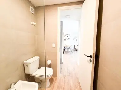 a bathroom with a toilet and a glass door at Departamento de lujo frente al quality espacio in Cordoba