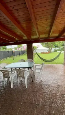 a table and chairs on a patio with a hammock at Casa Simaldo in Villa Carlos Paz