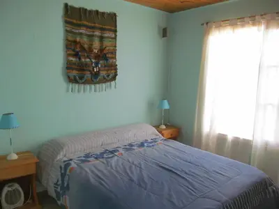 a bedroom with a bed and a blanket on the wall at Cabañas Likankurá in Santa Rosa de Calamuchita