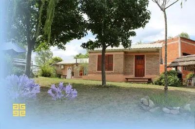 a house with purple flowers in front of it at Cabañas Likankurá in Santa Rosa de Calamuchita