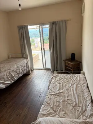 a bedroom with two beds and a sliding glass door at Departamento con increible vista in Villa Carlos Paz