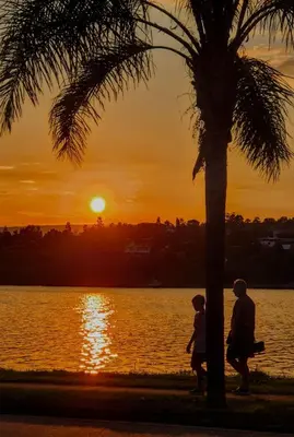 a man and a child walking under a palm tree at sunset at ANELE, duplex equipado in Villa Carlos Paz