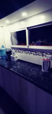 a kitchen with a black counter top and two windows at La Casita de Felipe in Santa Rosa de Calamuchita