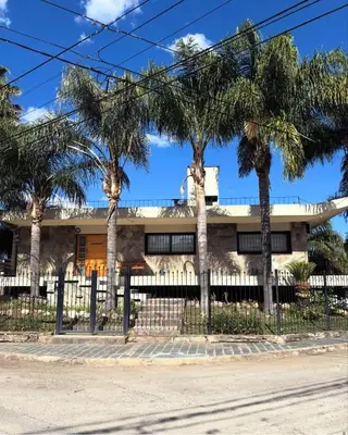 a house with palm trees in front of it at CASA LG carlos paz in Villa Carlos Paz