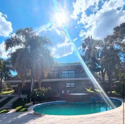 a fountain in front of a building with palm trees at CASA LG carlos paz in Villa Carlos Paz