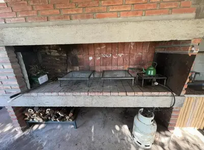 a brick fireplace with two benches and a green kettle at Cobiche in Villa Larca