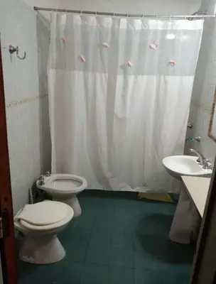 a bathroom with two toilets and a white shower curtain at casa carlos paz in Villa Carlos Paz