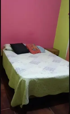 a bed in a room with a pink wall at casa carlos paz in Villa Carlos Paz