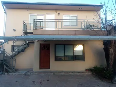 a house with a balcony and a door and a staircase at El Paraiso in Villa Carlos Paz