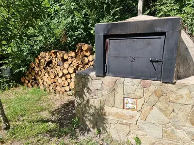 a stone wall with a wood stove next to a pile of logs at Casitas Santa Elena in Trapiche
