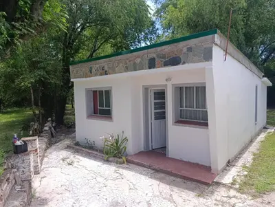 a small white building with a door and trees at Las Vertientes in Tanti