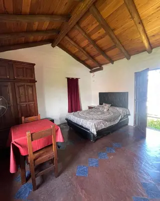 a bedroom with a bed and a table and chair at Casa rústica y departamento con wifi, cochera y asador a metros del río Mina Clavero in Mina Clavero