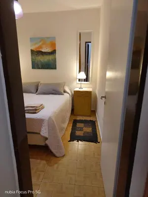 a small bedroom with a bed and a mirror at Marcelina in Villa Carlos Paz