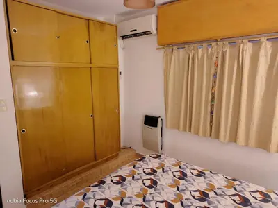 a bedroom with a bed and a wooden cabinet at Marcelina in Villa Carlos Paz