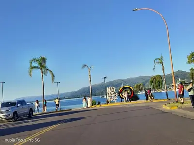 a group of people standing on a sidewalk near the water at Marcelina in Villa Carlos Paz