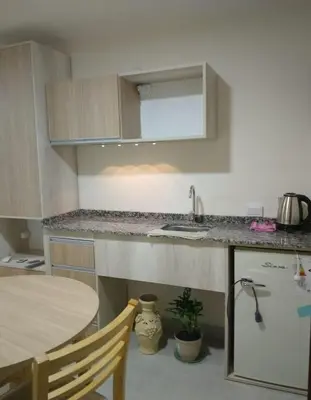 a kitchen with a table and a sink and a counter at La Pequeña Villa in Villa Carlos Paz