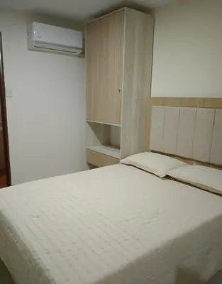 a bedroom with a large white bed and a cabinet at La Pequeña Villa in Villa Carlos Paz