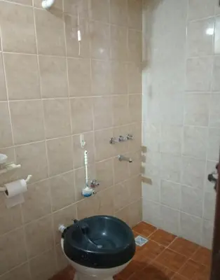 a bathroom with a toilet with a black seat at La Pequeña Villa in Villa Carlos Paz