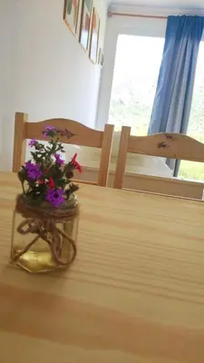 a vase with flowers sitting on a wooden table at Pasos del Dique in Cortaderas