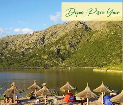 a group of umbrellas on a beach next to a lake at Pasos del Dique in Cortaderas
