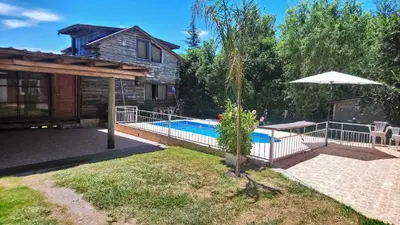 a pool in front of a house with an umbrella at Cabañas de San Antonio in San Antonio de Arredondo