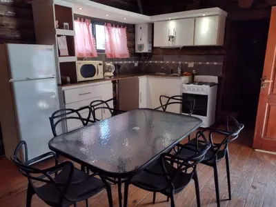 a kitchen with a table and chairs and a refrigerator at Cabañas de San Antonio in San Antonio de Arredondo