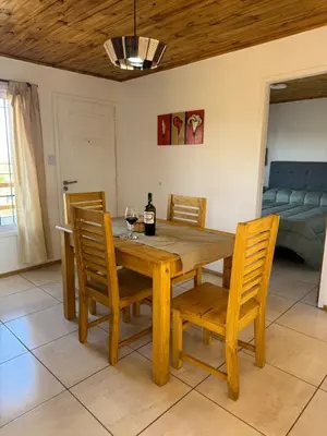 a dining room with a wooden table and chairs at Balcones del Cristal - Tacuarita in Tanti