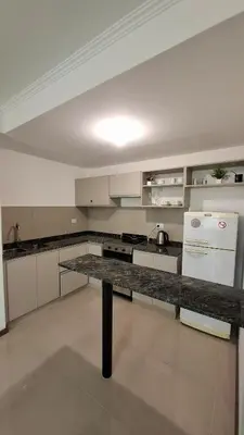 a large kitchen with a counter and a refrigerator at Departamento Premium en el corazón de Villa Carlos Paz in Villa Carlos Paz
