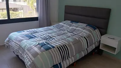a bed with a striped comforter in a room with a window at Dpto Premium Frente al lago in Villa Carlos Paz