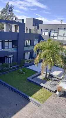 a building with a palm tree in front of it at Dpto Premium Frente al lago in Villa Carlos Paz