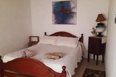 a bedroom with a wooden bed with white sheets at Paraiso Cabañas in La Ramada