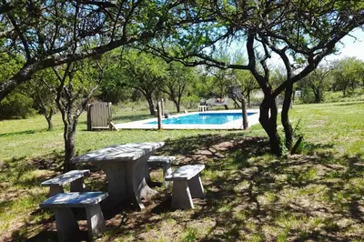 a picnic table and benches in a park with a swimming pool at Paraiso Cabañas in La Ramada