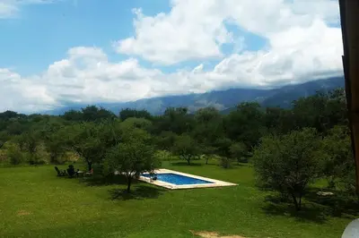 a swimming pool in a field with mountains in the background at Paraiso Cabañas in La Ramada