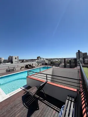 a deck with chairs and a swimming pool on a building at Departamento en el Centro Completo, Cochera, Pile, Pile Clim in Villa Carlos Paz